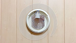 An old plafond with a removed light bulb hangs on a wall from a wooden lining.