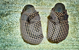 Old plaid worn slippers on an old carpet