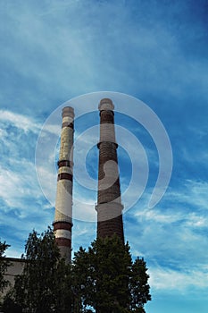 Old plant pipes on blue sky background. Industrial heat-energy center