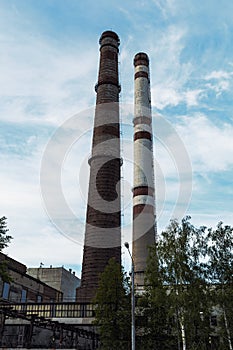 Old plant pipes on blue sky background. Industrial heat-energy center with tall chimney tubes