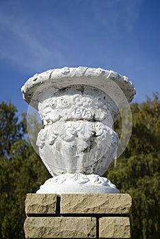 Old plaster garden vase on a modern brick pedestal