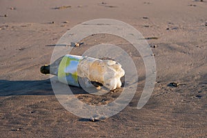 Old plastic bottles on a sandy beach.