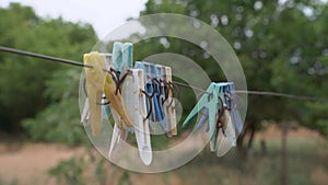Old plastic clothespins hang on rope for traditional way of drying washed laundry in countryside, swing in wind, close