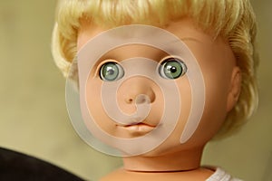 Old plastic doll with blonde hair.