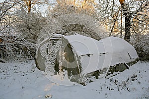 Old plastic greenhouse in derelict farm and snow