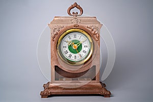 Old plastic table clock with gold stopped hands. Brown vintage watch with round white green dial and Roman numbers on