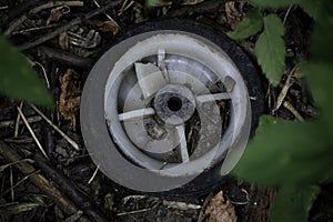 The old plastic wheel lays on a ground in the forest