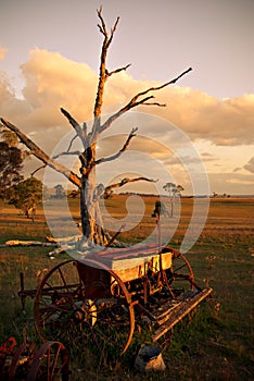 Old plough on farm at sunset