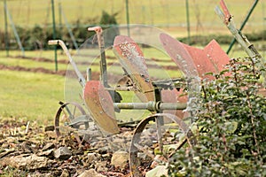An old ploughing tool. Two-row rotary plough for ploughing. Background of a vineyard