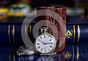 Old pocket watch and books on a mirror surface