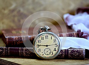 Old pocket watch and books on a table. Vintage still