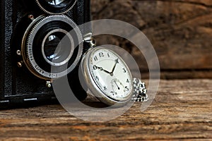 Old pocket watch and chain, vintage locket watch on chestnut rustic wooden background with retro camera