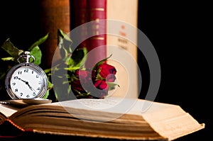 Old pocket watch in focus on old opened book