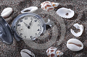 An old pocket watch lying in the sand.