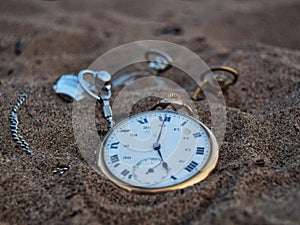 Old pocket watch in the sand.