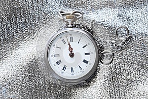 old pocket watch on silver fabric background