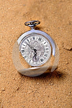 Old pocketwatch laying on the sand
