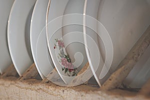 Old porcelain plates with floral decoration in wooden shelf -