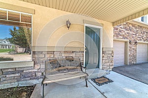 Old porch bench against stone brick wall of home with green wood front door