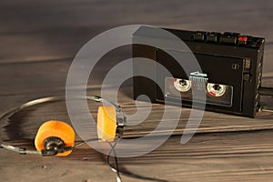 Old portable cassette player and headphones on a wooden background