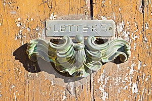Old postal brass mailbox gainst a colored wooden door photo