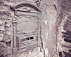 Old postal mailbox against a damaged stone and brick wall