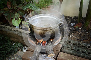 Old pot standing on the wood-burning stove with steam from cooking