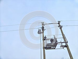 Old power line pole and transformer against blue sky in sunny day