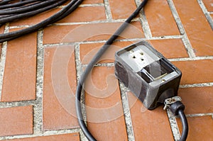 Old power outlet on brown floor tile