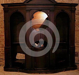 old priest inside the confessional waiting for the faithful to c
