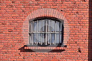 The old prison window on the red brick wall