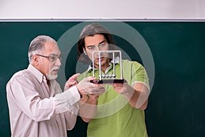 Old professor physicist and young student in the classroom