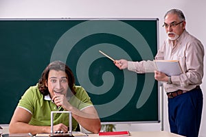 Old professor physicist and young student in the classroom