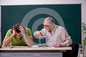 Old professor physicist and young student in the classroom