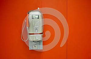 Old public phone on a red wall
