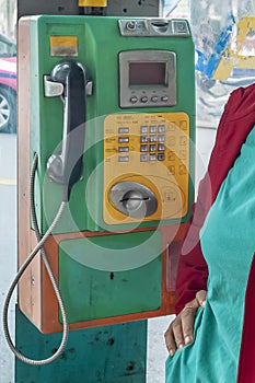 An old public telephone with keypad in a booth in central Bangkok, Thailand