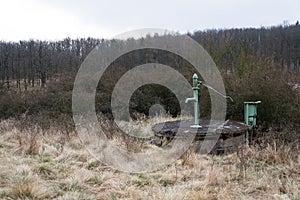 Old pump with leafless forest, water shortage scarcity concept