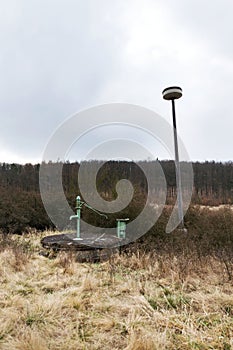 Old pump with leafless forest, water shortage scarcity concept