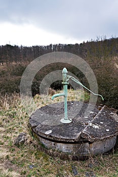 Old pump with leafless forest, water shortage scarcity concept