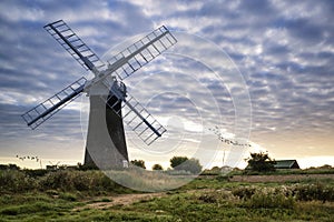 Old pump windmill in English countryside landscape early morning