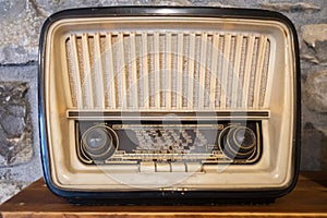 an old radio on a shelf on a stone background with volume, tone and tuning controls, with the name of the cities on the frequency