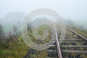 Old railroad and house vanishing in fog