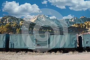 Old Railroad Train Green Box Car in front of Mountains and Clouds