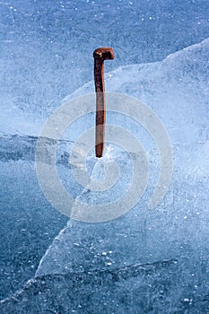 Old railway crutch hammered into the ice of a lake.