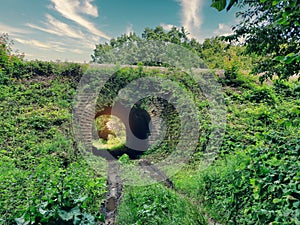 Starý železniční tunel pod železnicí, zarostlý trávou a mechem