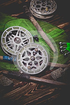 Old rarity bottom fishing reels on a wooden background. Bell, fish tank and makuha cubes