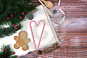 Old recipe book, fir branches and gingerbread man on the wooden background. Christmas baking. Copy space. Top view