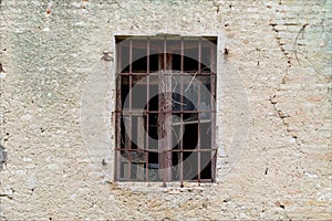 Old window, with iron bars, on abandoned building facade.