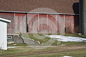 Old red barn in early winter with just a touch of snow on a sunny day on a farm