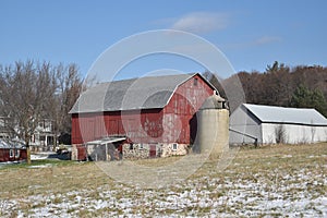 Old red barn in early winter with just a touch of snow on a sunny day on a farm